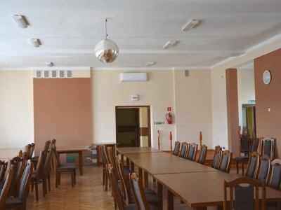 Widok całej sali w Wiejskim Domu Kultury w Markowcach, gmina Sanok. Widać dwa rzędy stołów i krzesła. Pod sufitem na środku sali widać kule dyskotekową.