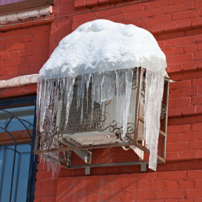 Jednostka zewnętrzna klimatyzacji, pokryta lodem zimą.